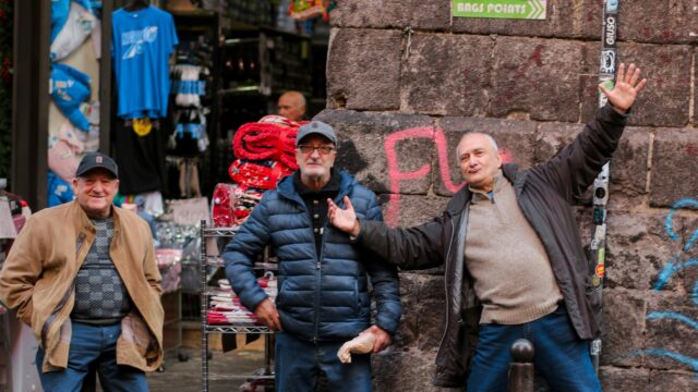 Three Cheerful Italian Men Standing on a Charming Street Desktop Wallpaper