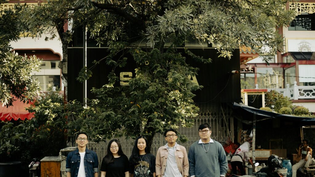 Group of Friends Standing Under a Tree in an Urban Setting Desktop Wallpaper