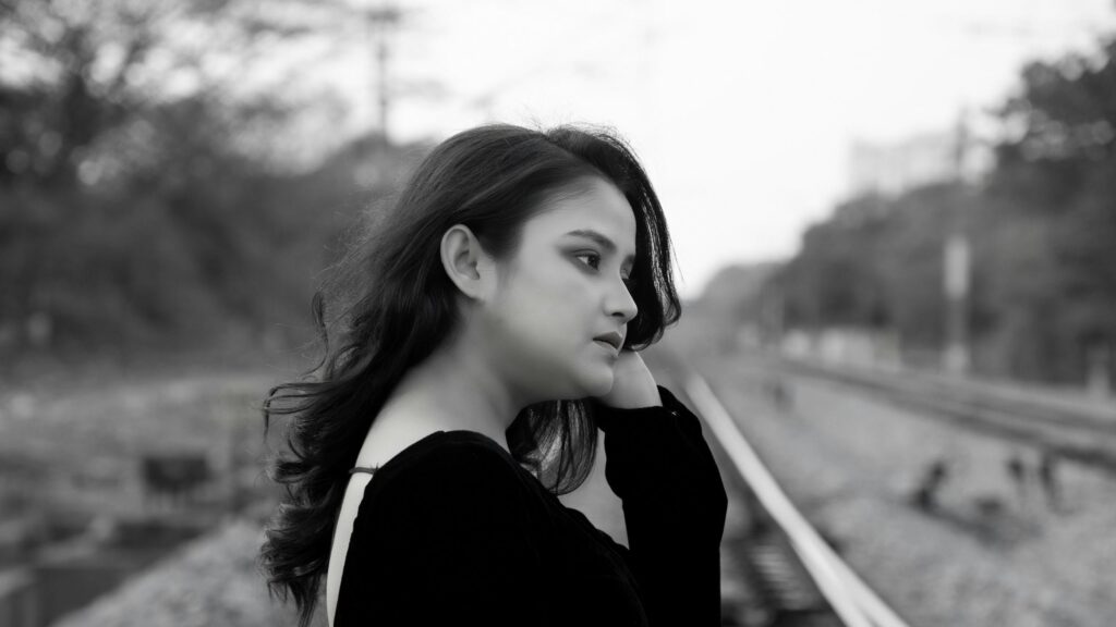 Sad Young Woman Standing on Railway Tracks Black and White Desktop Wallpaper