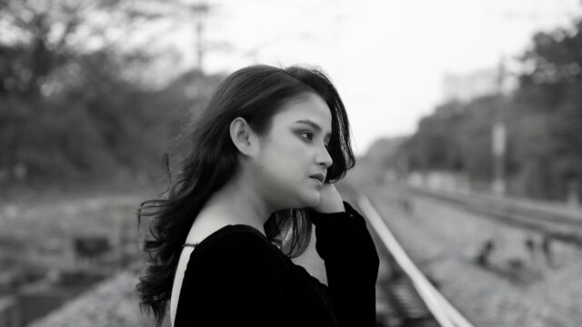 Sad Young Woman Standing on Railway Tracks Black and White Desktop Wallpaper
