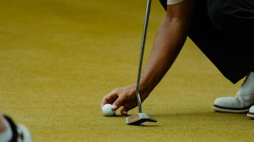 Professional Golfer Preparing for a Putt on Green Grass Desktop Wallpaper