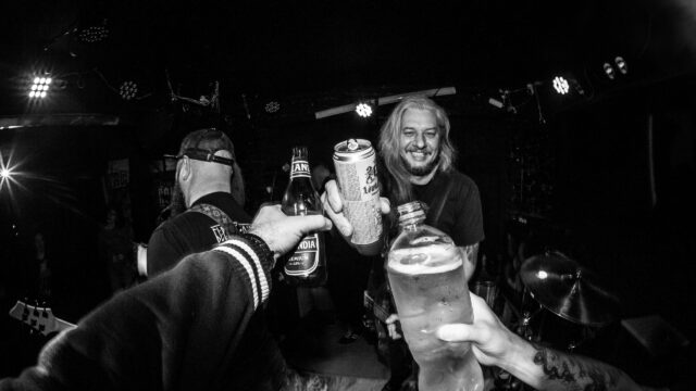 Band Members Celebrating with Drinks on Stage 4K Wallpaper
