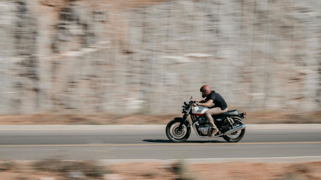 Speeding Royal Enfield Motorcycle on Open Road Desktop Wallpaper