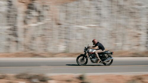 Speeding Royal Enfield Motorcycle on Open Road Desktop Wallpaper
