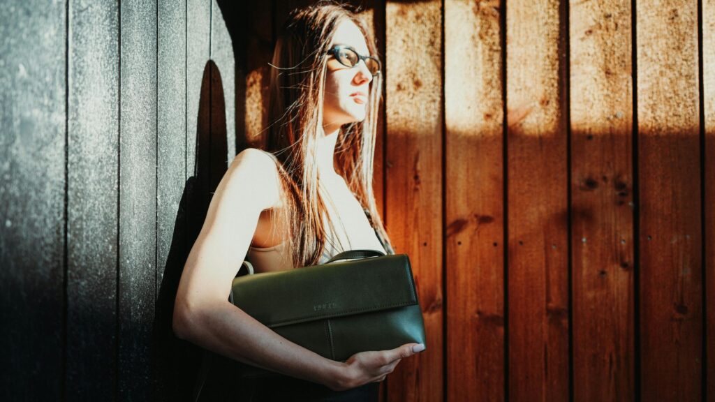 Stylish Woman with Olive Green Handbag by Wooden Wall 4K Desktop Wallpaper