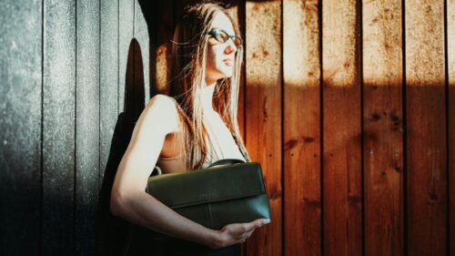 Stylish Woman with Olive Green Handbag by Wooden Wall 4K Desktop Wallpaper