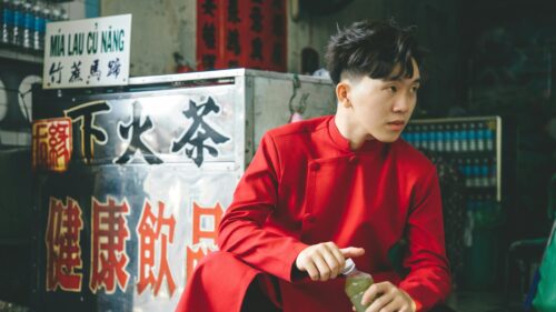 Young Man in Traditional Red Outfit at Street Drink Stall Desktop Wallpaper