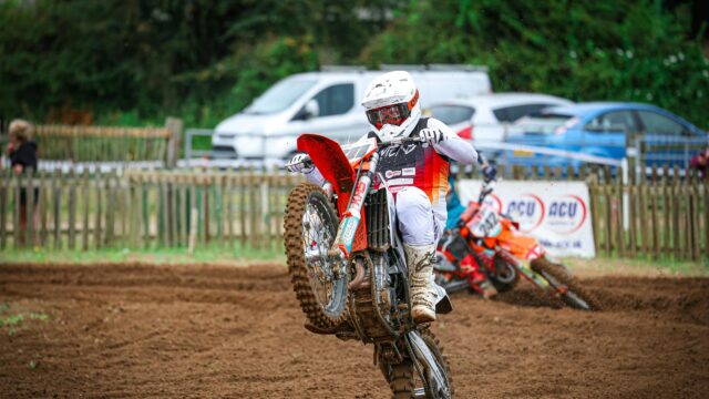Motocross Rider Performing a Wheelie on Dirt Track Desktop Wallpaper