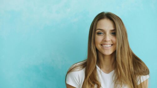 Beautiful Smiling Young Woman with Long Hair on Blue Background 4K Wallpaper