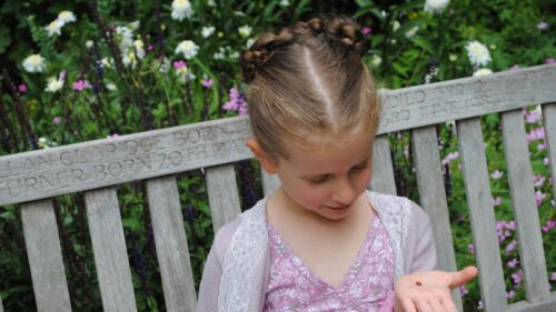 Little Girl Holding Ladybug on Garden Bench Desktop Wallpaper