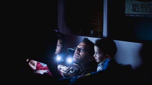 Father Reading Bedtime Stories to Kids with Flashlight 4K Wallpaper