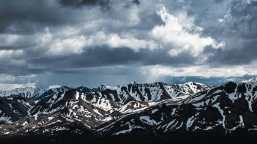 Dramatic Snowy Mountain Range Under Stormy Clouds 4K Wallpaper