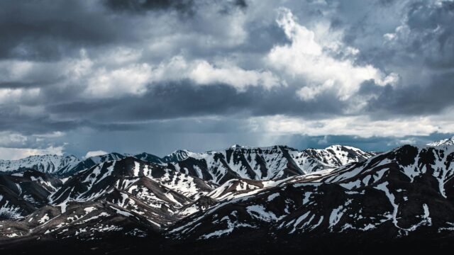 Dramatic Snowy Mountain Range Under Stormy Clouds 4K Wallpaper