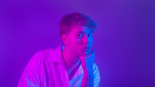 Young Man in White Shirt with Vibrant Neon Lighting 4K Wallpaper