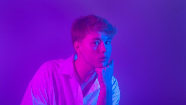 Young Man in White Shirt with Vibrant Neon Lighting 4K Wallpaper