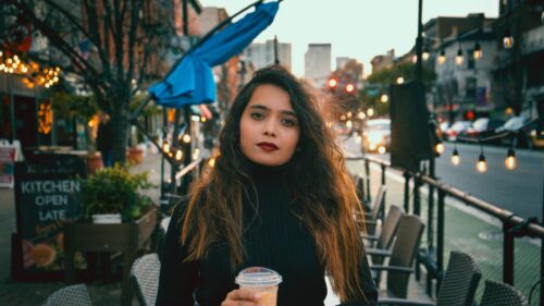 Woman with Long Wavy Hair Drinking Coffee Urban Street 4K Wallpaper