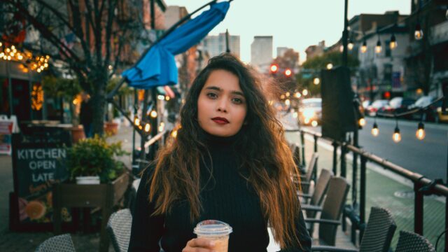 Woman with Long Wavy Hair Drinking Coffee Urban Street 4K Wallpaper