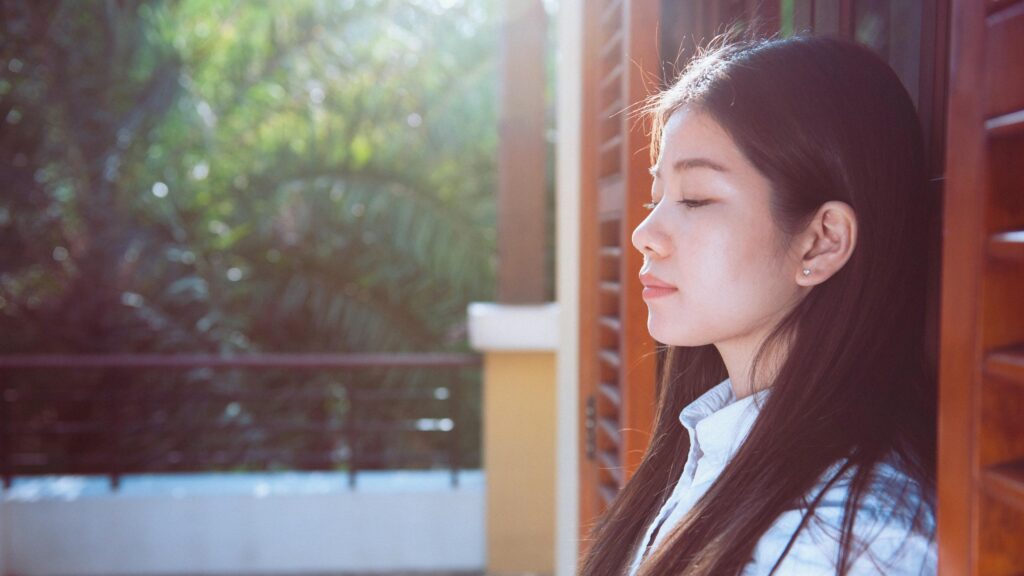 Serene Woman Leaning on Wooden Shutters Sunlit Portrait 4K Wallpaper