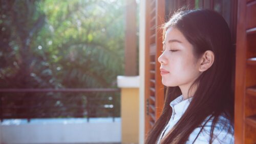 Serene Woman Leaning on Wooden Shutters Sunlit Portrait 4K Wallpaper