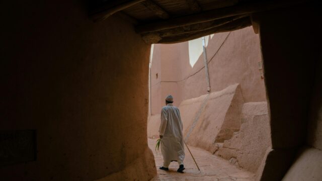Man Walking Through Ancient Clay Alleyway 4K Desktop Wallpaper