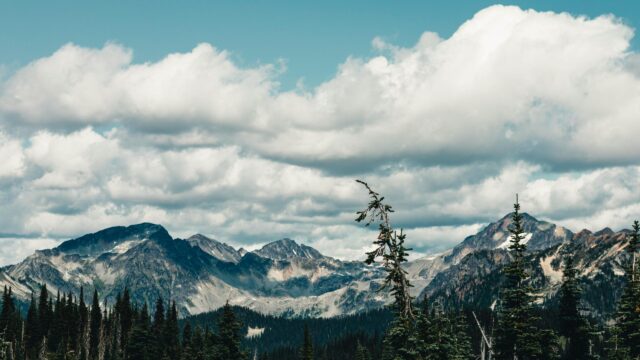 Majestic Mountain Range with Pine Trees and Dramatic Clouds PC Wallpaper
