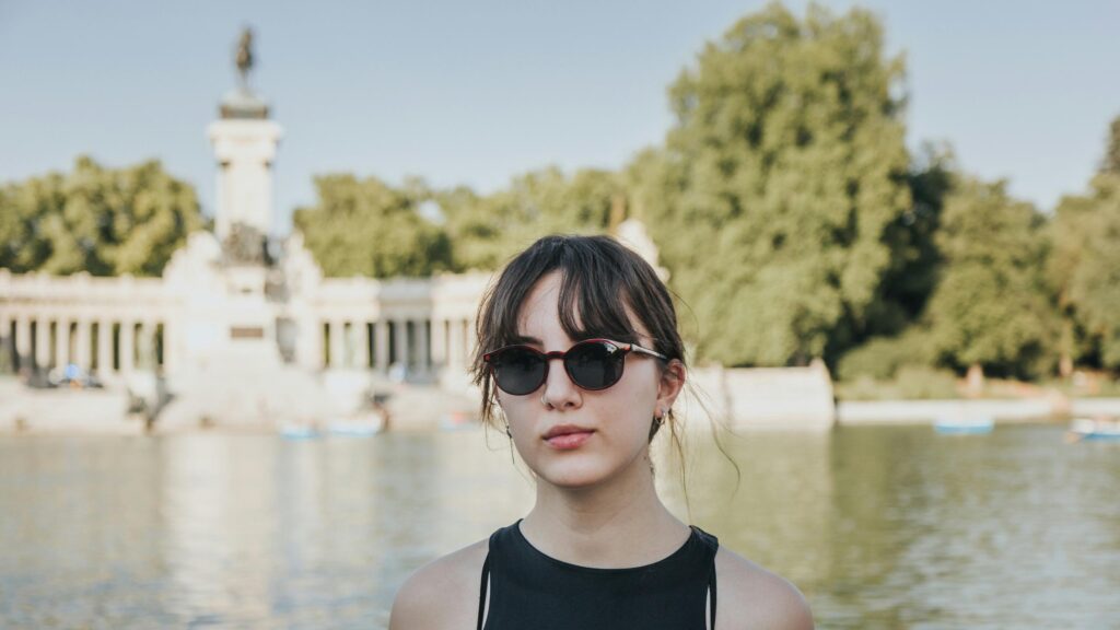Stylish Woman in Sunglasses by a Scenic Lake Park Desktop Wallpaper
