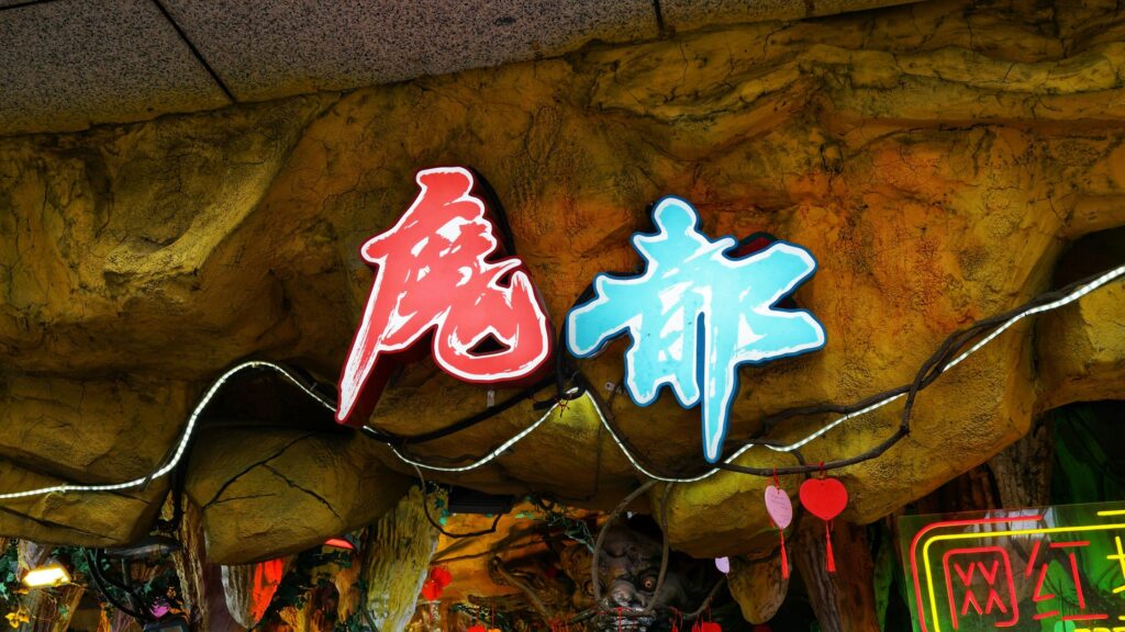 Neon Chinese Characters On Textured Cave Wall 4K Wallpaper