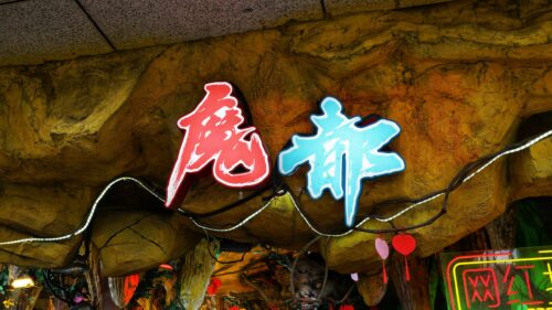 Neon Chinese Characters On Textured Cave Wall 4K Wallpaper