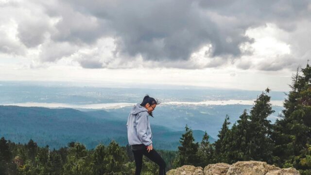 Adventurous Girl Overlooking a Coastal City Landscape Desktop Wallpaper