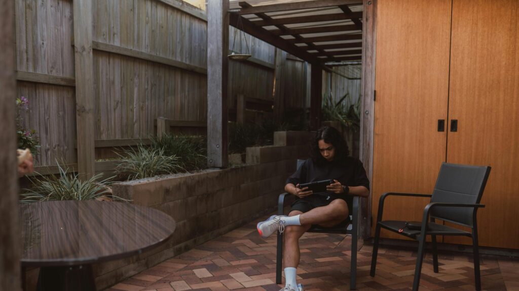 Relaxed Young Man Gaming on Patio Handheld Console 4K Wallpaper