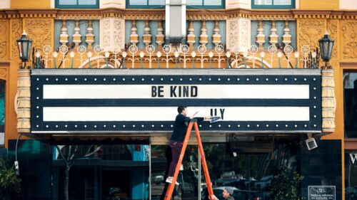 Man Placing Be Kind Lettering on Historic Theater Marquee 4K Wallpaper