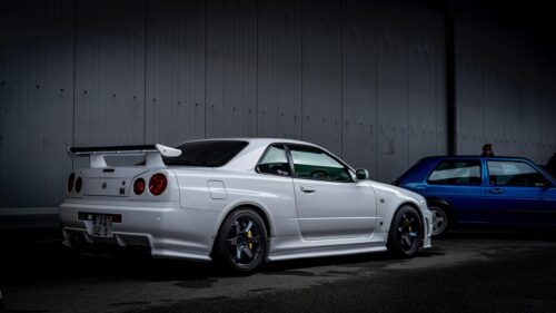 White Nissan Skyline GT-R R34 and Blue Hatchback 4K Desktop Wallpaper