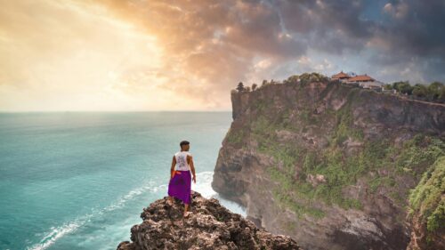 Man Standing on Cliff Overlooking Uluwatu Temple Bali 4K Wallpaper