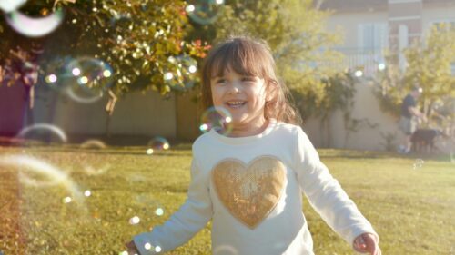 Little Girl Playing with Bubbles in Sunny Garden 4K Desktop Wallpaper