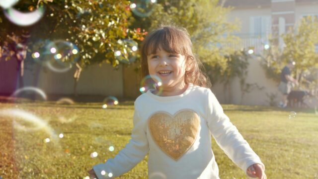 Little Girl Playing with Bubbles in Sunny Garden 4K Desktop Wallpaper