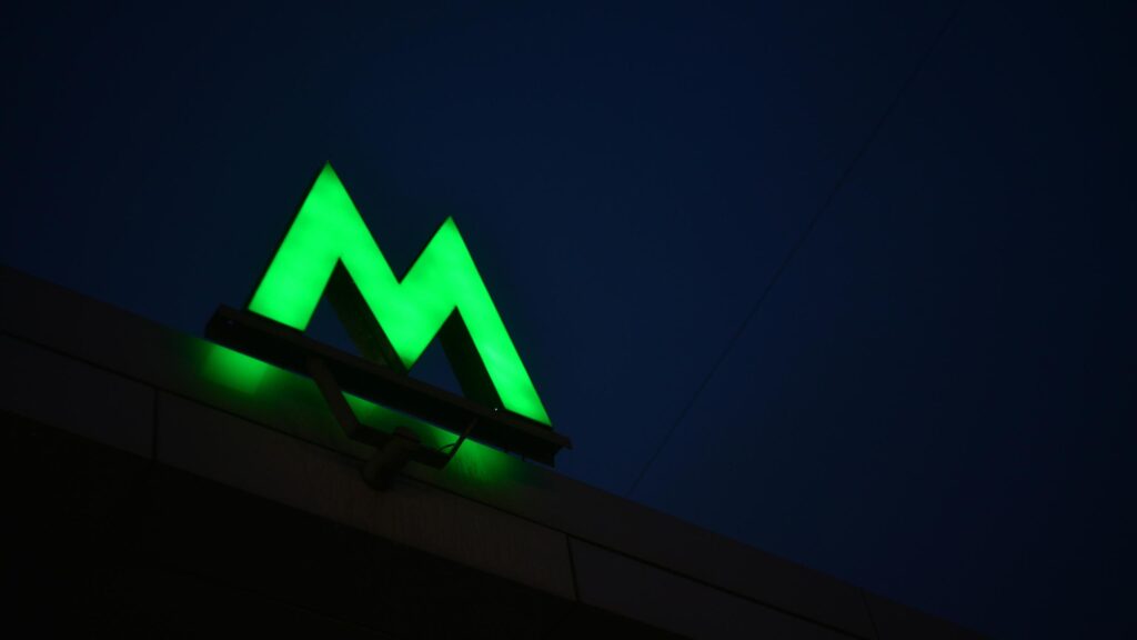 Glowing Green Metro Sign Against Dark Night Sky 4K Wallpaper