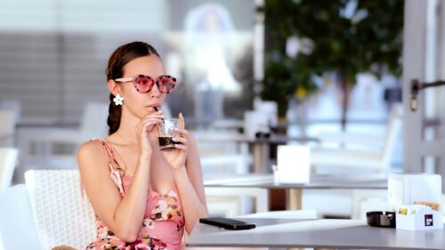 Stylish Woman in Pink Floral Dress Drinking Iced Coffee Desktop Wallpaper