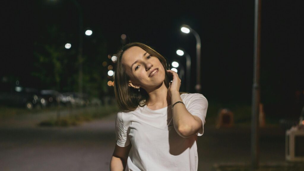 Young Woman Smiling Under Night Street Lights 4K Desktop Wallpaper