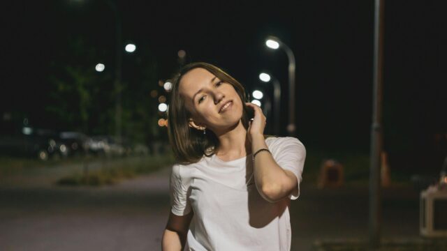 Young Woman Smiling Under Night Street Lights 4K Desktop Wallpaper