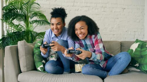 Excited Sisters Playing Video Games on Couch Desktop Wallpaper