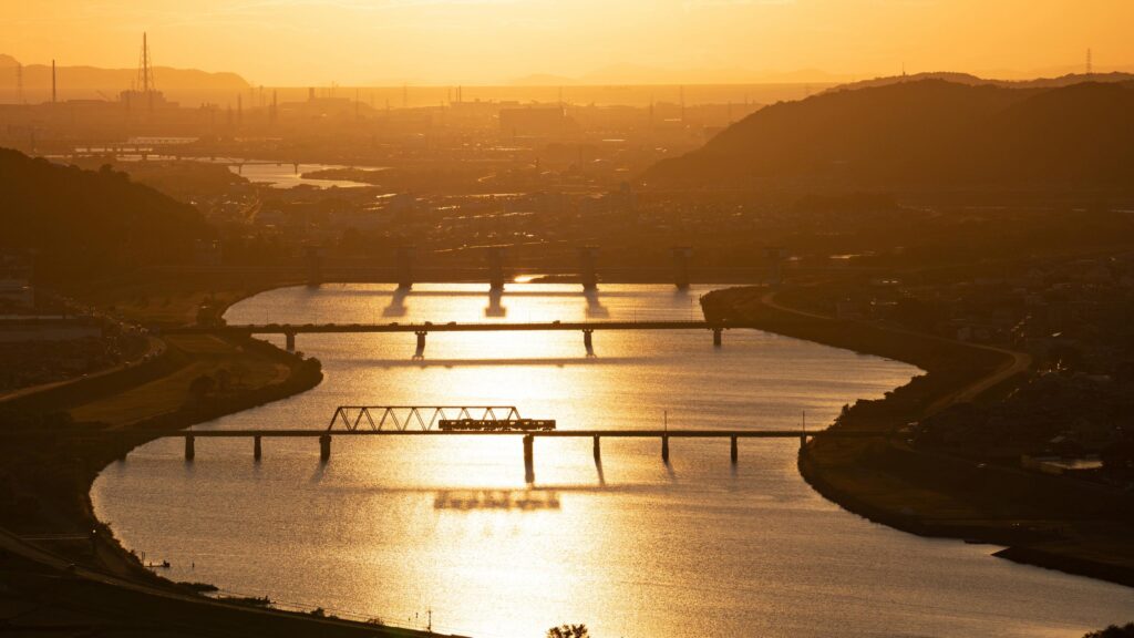Golden Hour Train Crossing Over a Serene River Landscape Desktop Wallpaper