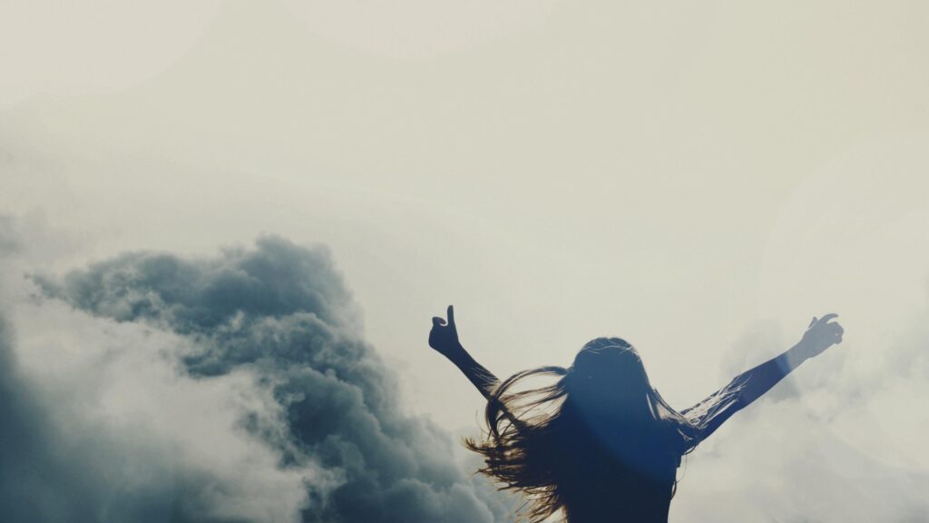 Silhouette of a Woman Celebrating Freedom Above the Clouds 4K Desktop Wallpaper