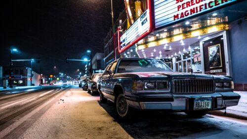 Vintage Car Parked Under Theater Lights on a Snowy Night Desktop Wallpaper