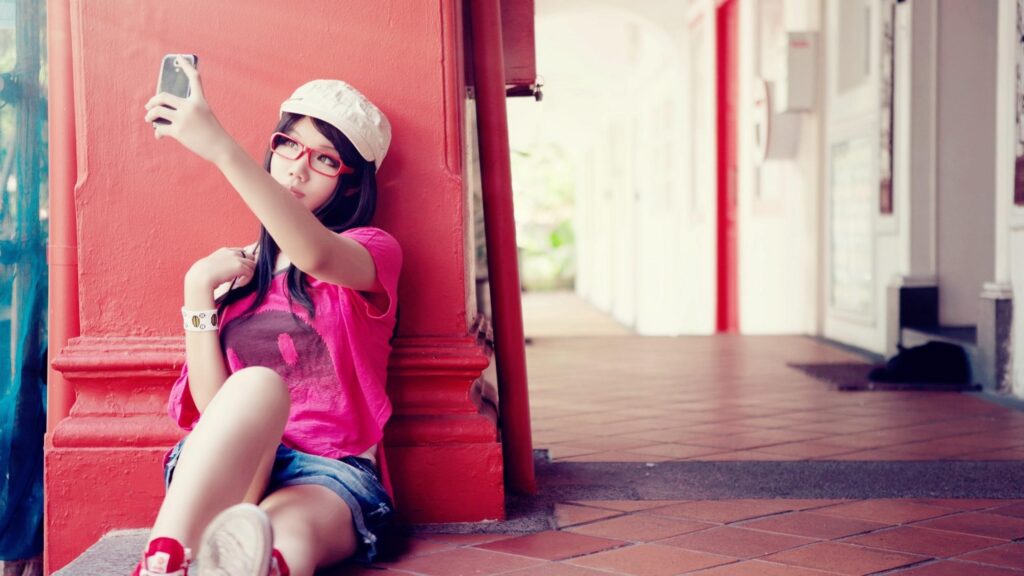 Stylish Girl Taking Selfie Against Red Pillar Desktop Wallpaper