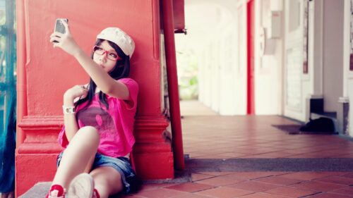 Stylish Girl Taking Selfie Against Red Pillar Desktop Wallpaper