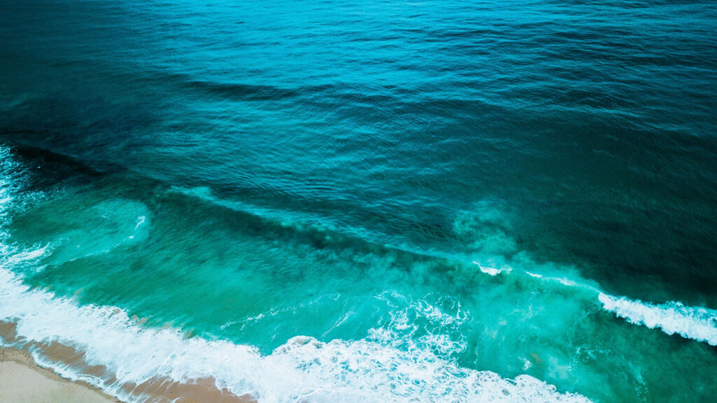 Stunning Aerial View of Turquoise Ocean Waves Rolling to Shore PC Wallpaper