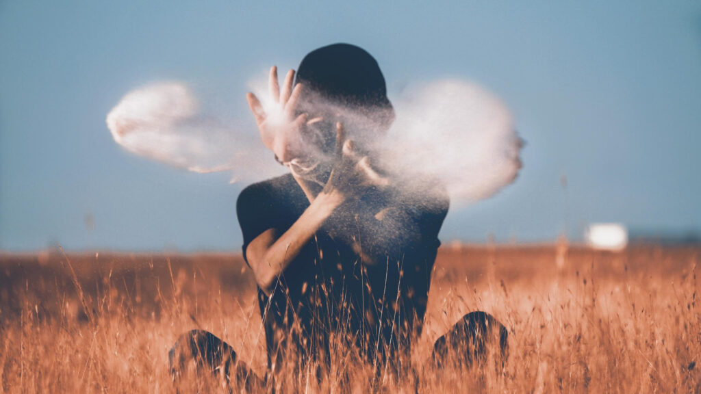 Person Sitting in Golden Grass with Powder Clouds Desktop Wallpaper