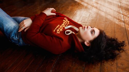 Dreamy Young Woman in Red Hoodie Lying on Rustic Wooden Floor 4K Wallpaper