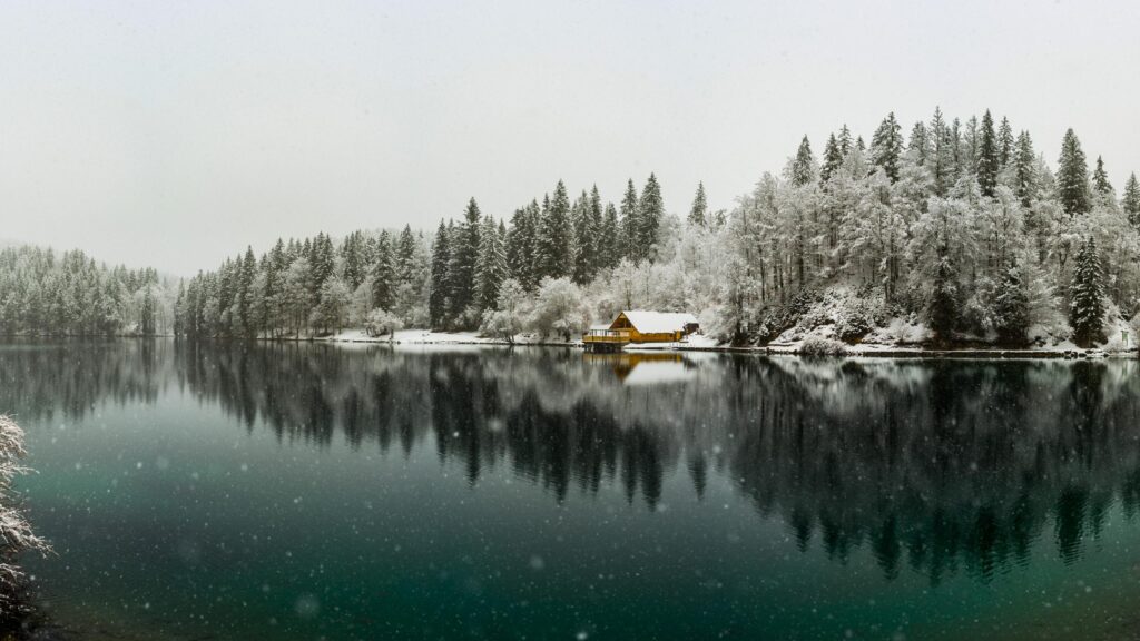 Serene Yellow Cabin by a Snowy Alpine Lake Winter Desktop Wallpaper