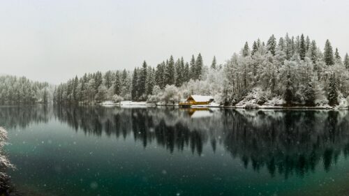 Serene Yellow Cabin by a Snowy Alpine Lake Winter Desktop Wallpaper